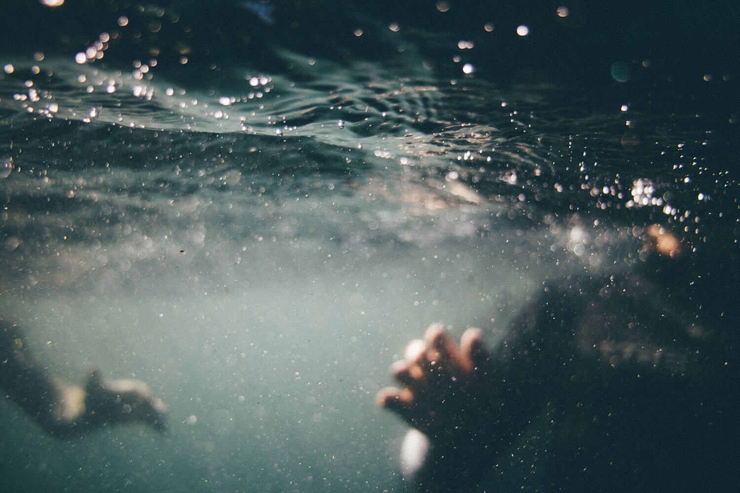 Abstract photo of water with two blurry hands underwater.