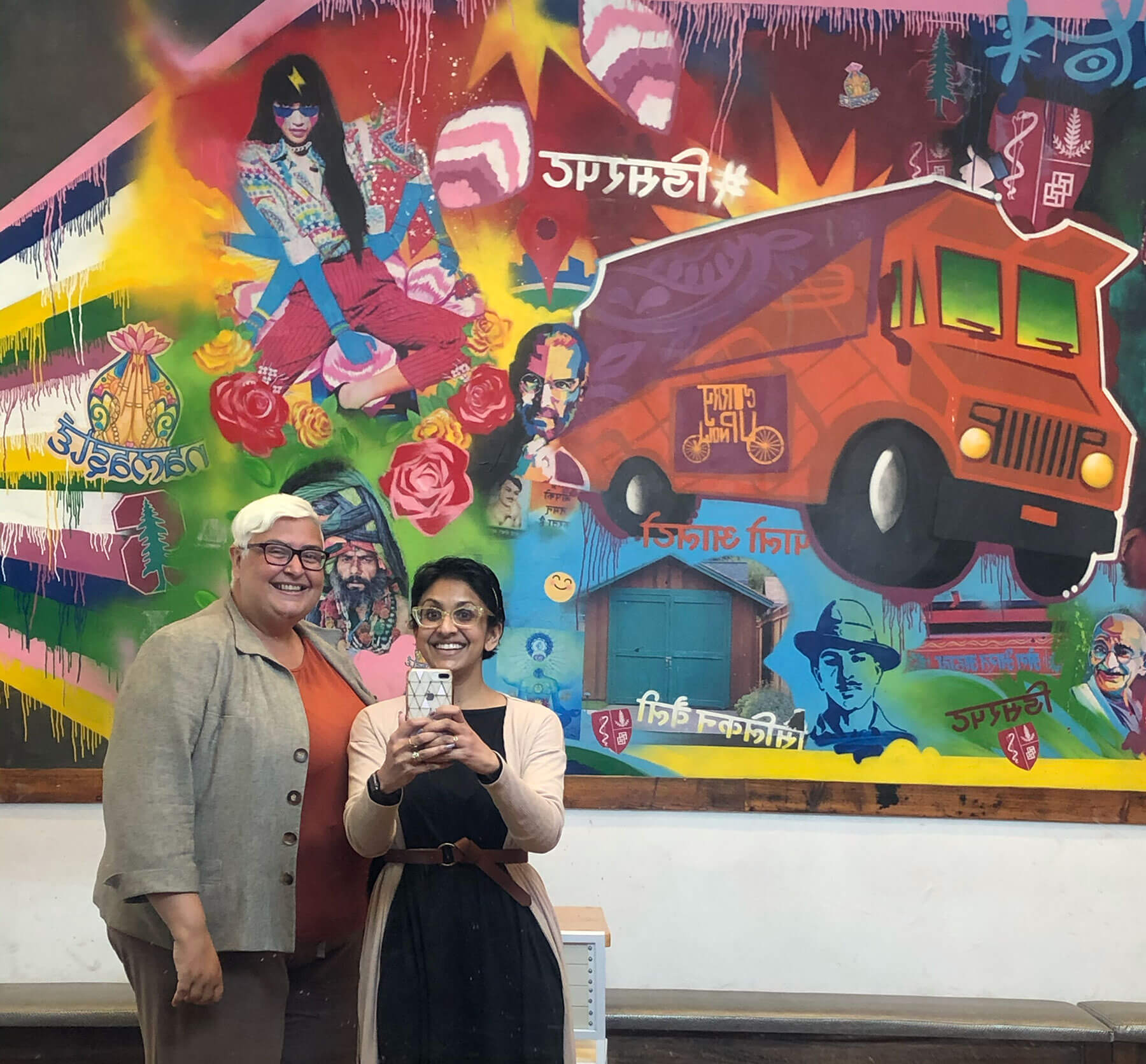 Sandhya Jha and Tuhina Verma Rasche take a selfie in front of a mural at Curry Up Now