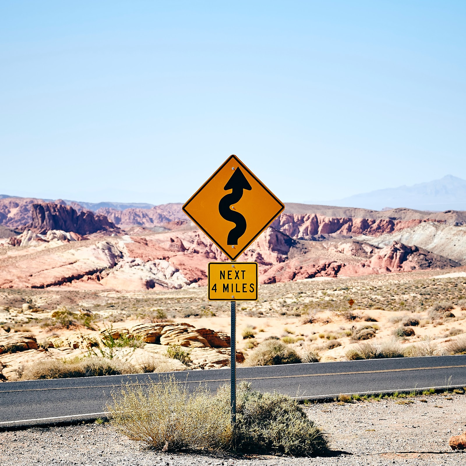 A road sign in the desert of Nevada showing that the next 4 miles there will be curves