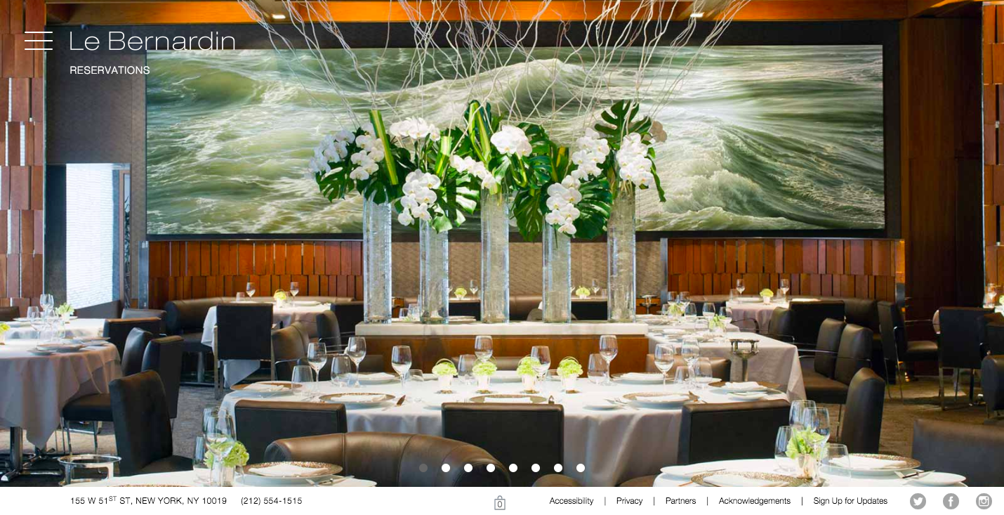 Le Bernardin homepage hero section. The inside of the empty restaurant with fancy table settings, linen cloths, and a flower display in front of a large ocean painting that covers most of the back wall.