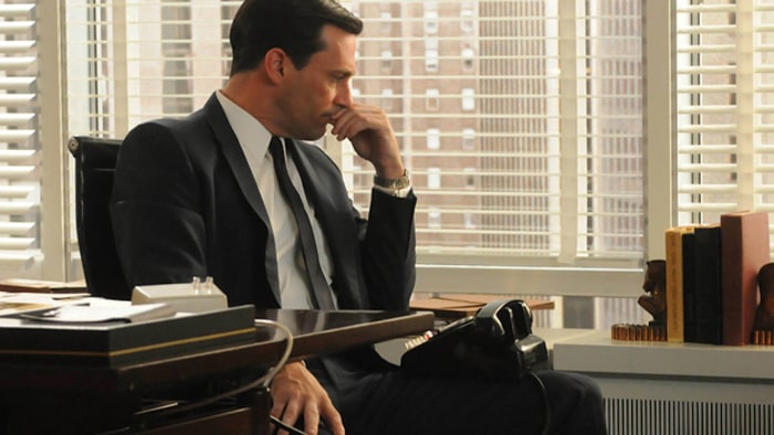 Don Draper in a thinking pose at his office desk.