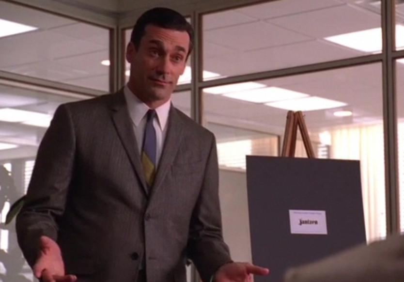 Don Draper in front of an easel with mockups.