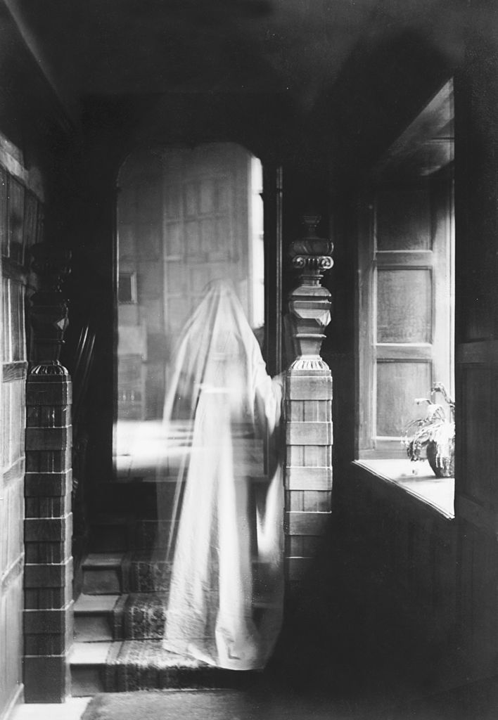 Black and white image of a transparent figure walking up the stairs.