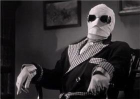 A screenshot of the main character from the movie Invisible Man. His face is wrapped in gauze and he's wearing sunglasses, sitting in a chair.