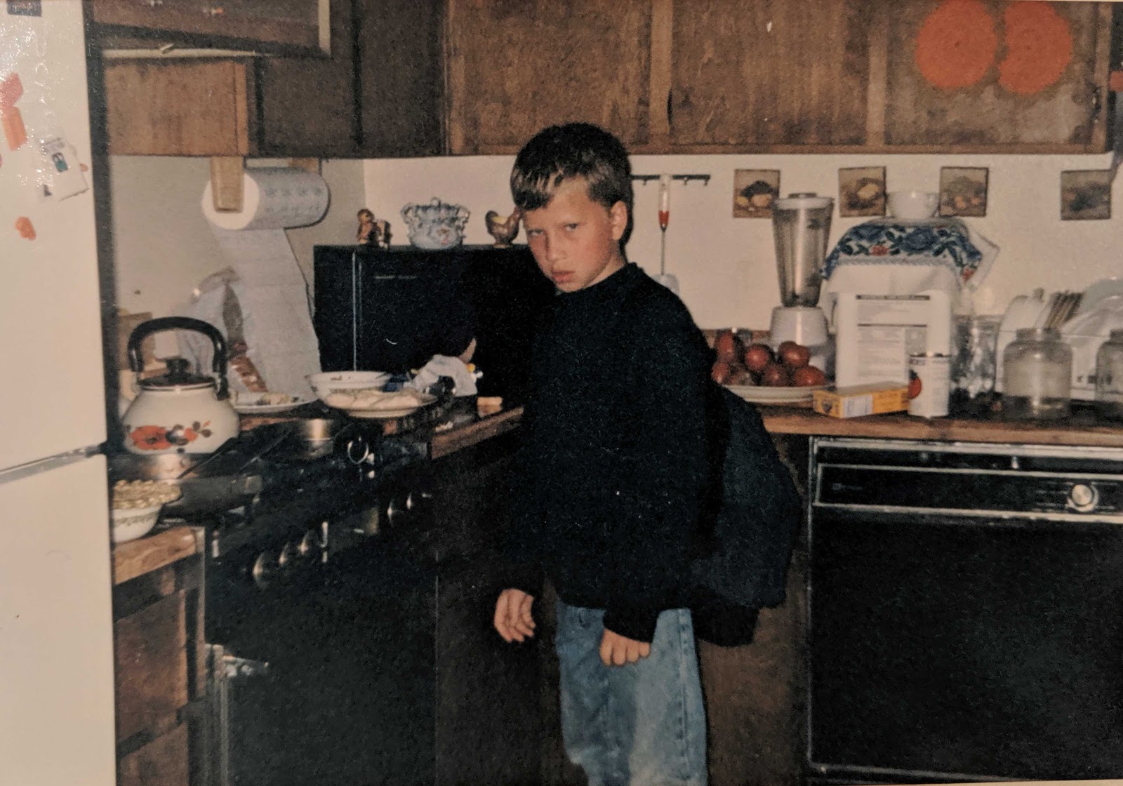 A young Vlad Magdalin stands in a kitchen with a scowl on his face.