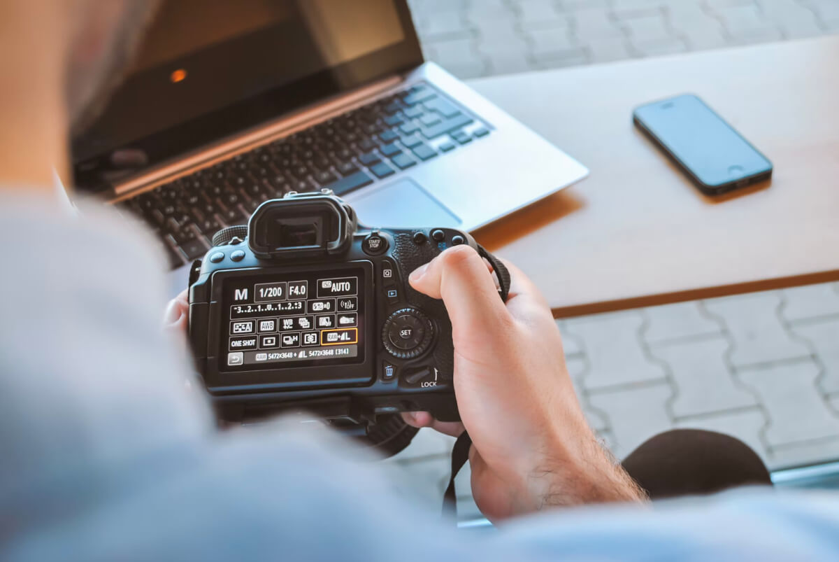 this image shows a person sat in front of a laptop configuring the photography setting on a professional camera