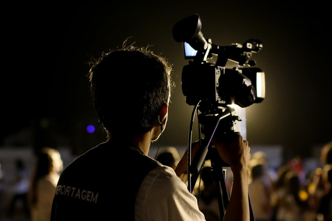 A video camera person against a dim light