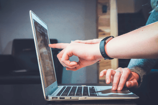 Two persons using a laptop placed on a desk