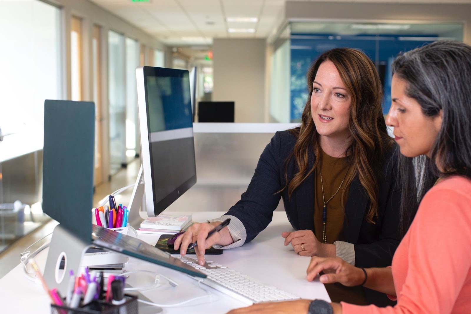 two women wearing business attire and using a laptop