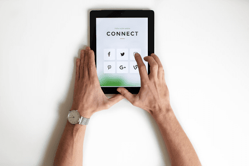 Hands of a man selecting a social media icon displayed on a tablet