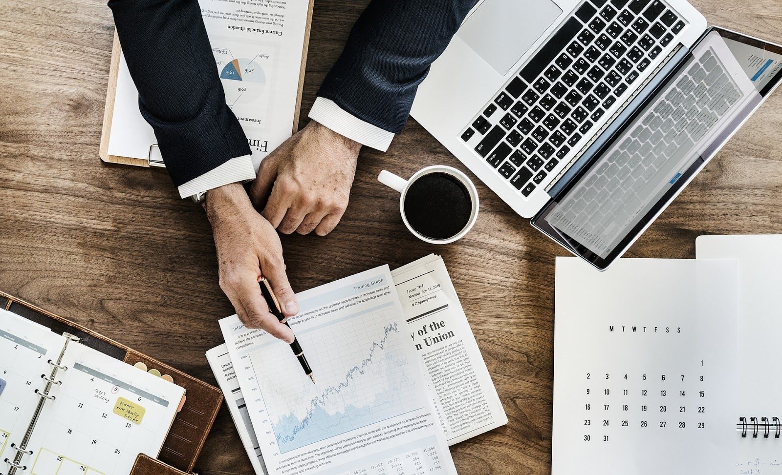 Man pointing at sales management strategies with pen and coffee