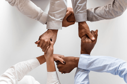 Four people interlocking their hands in a square shape.