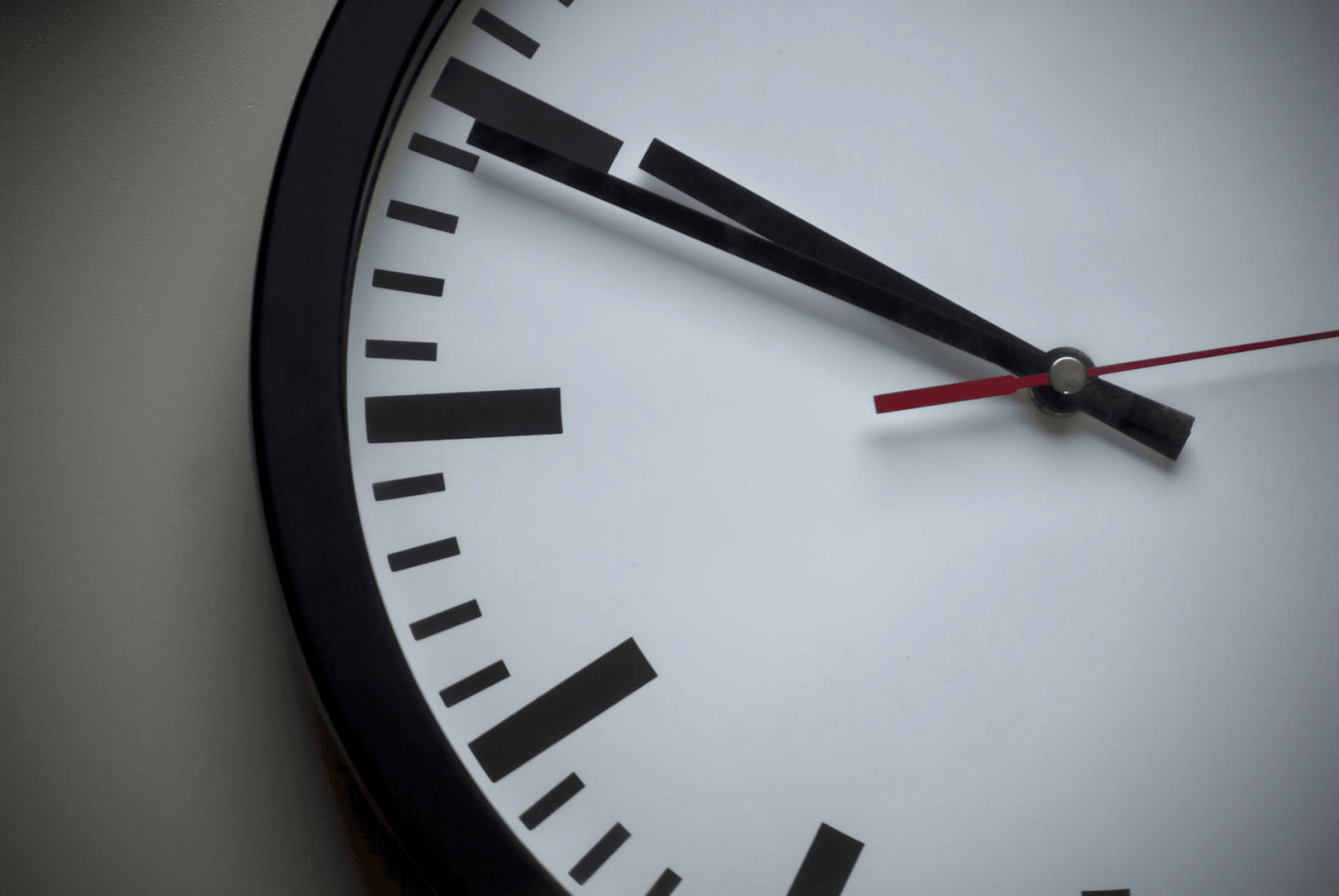 A black and white analog clock with a red seconds hand.