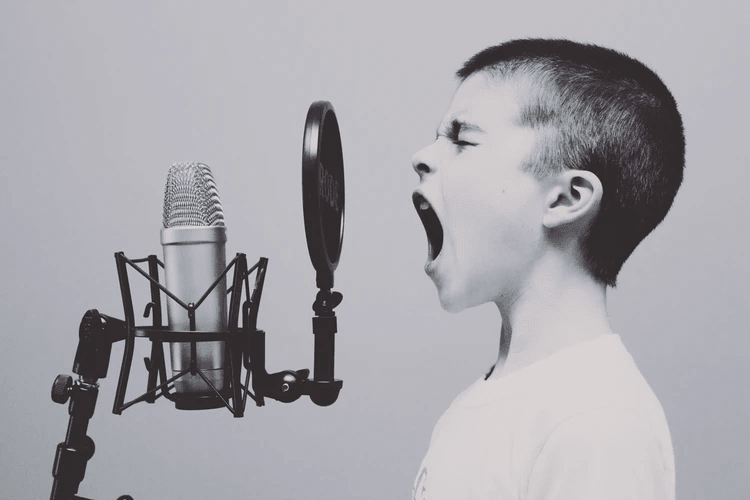 A young boy singing into a microphone.