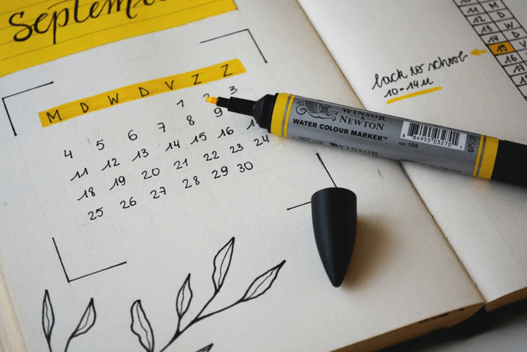 A physical calendar book with a yellow pen.