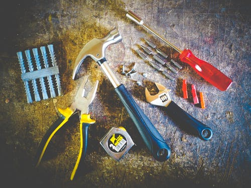 A pile of tools including a hammer, tape measure, and wrench.