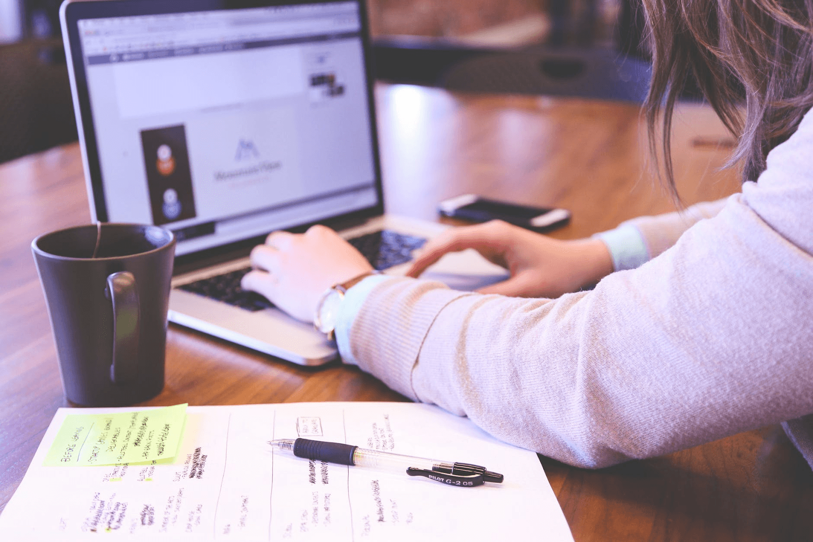 Woman working at a computer with a cup of coffee.