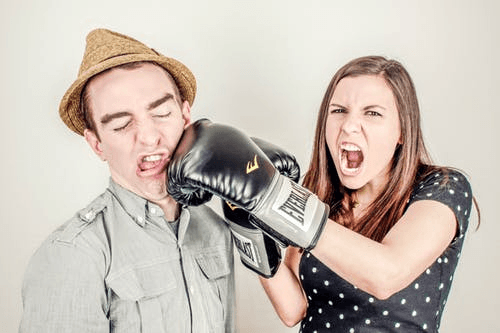 A woman with boxing gloves punching a man in the face.