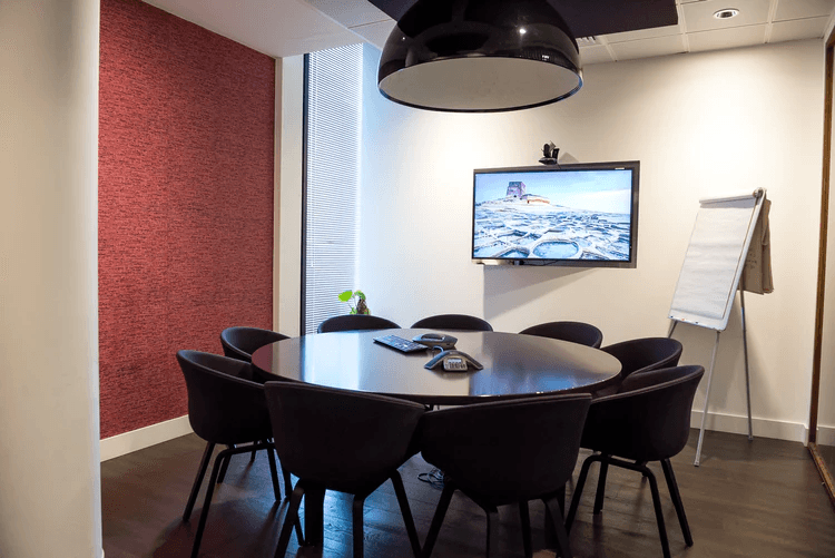 A video conference room complete with table, chairs, and TV screen.