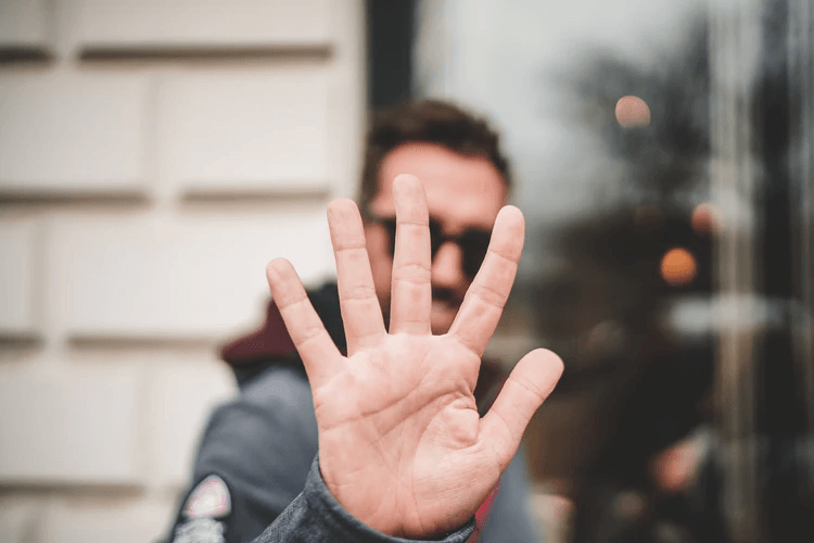 A man holding up his five fingers to the camera.