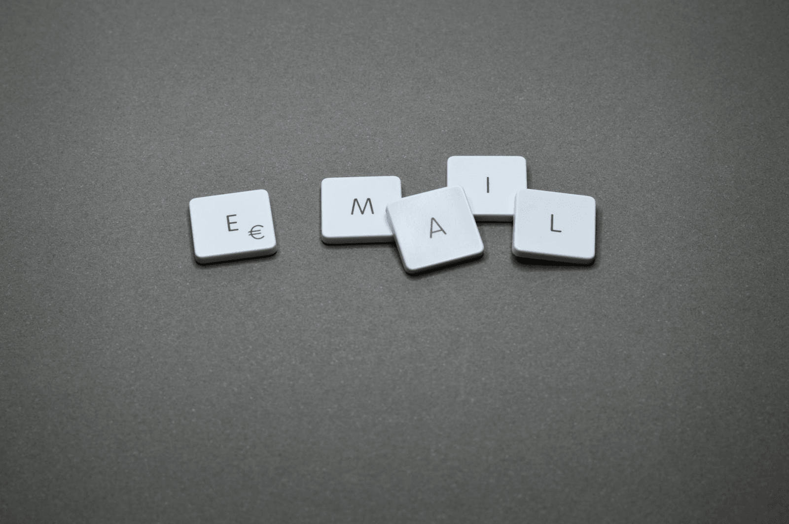 The word "email" spelled out with loose keyboard letters against a gray background.