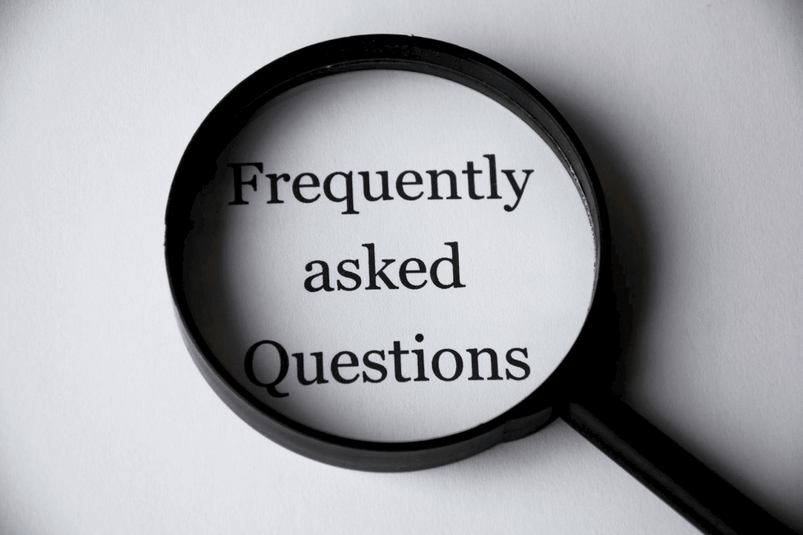 A magnifying glass centered on the words "Frequently Asked Questions".