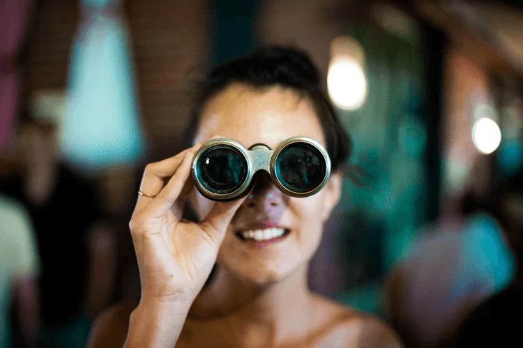 A woman holding binoculars to her face.