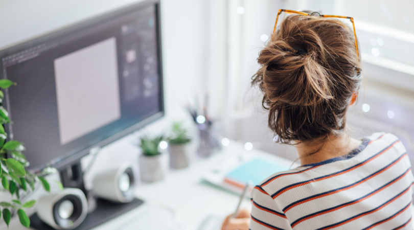 Woman in front of monitor looking out window