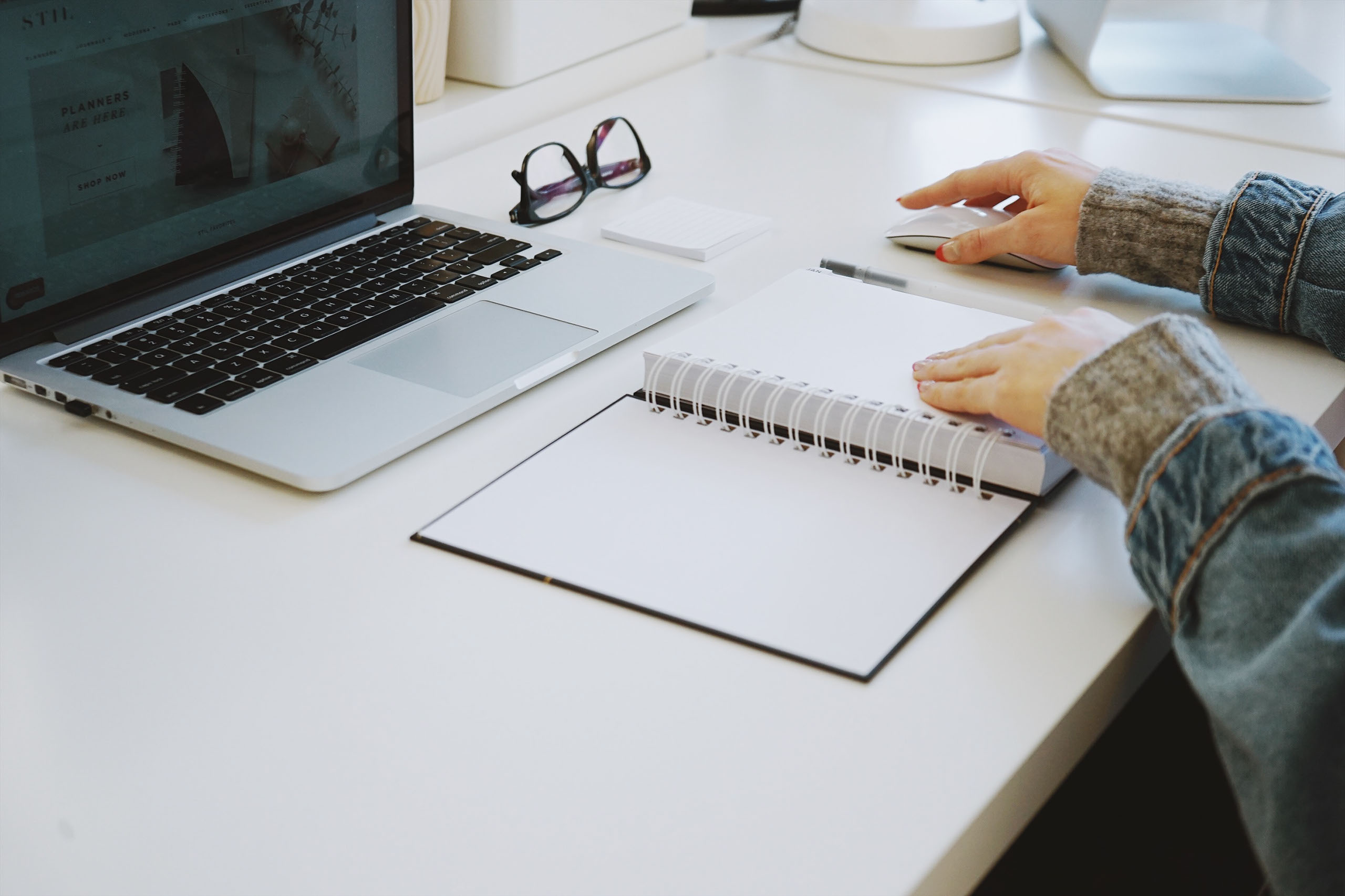 Woman using mouse with laptop and notebook in front