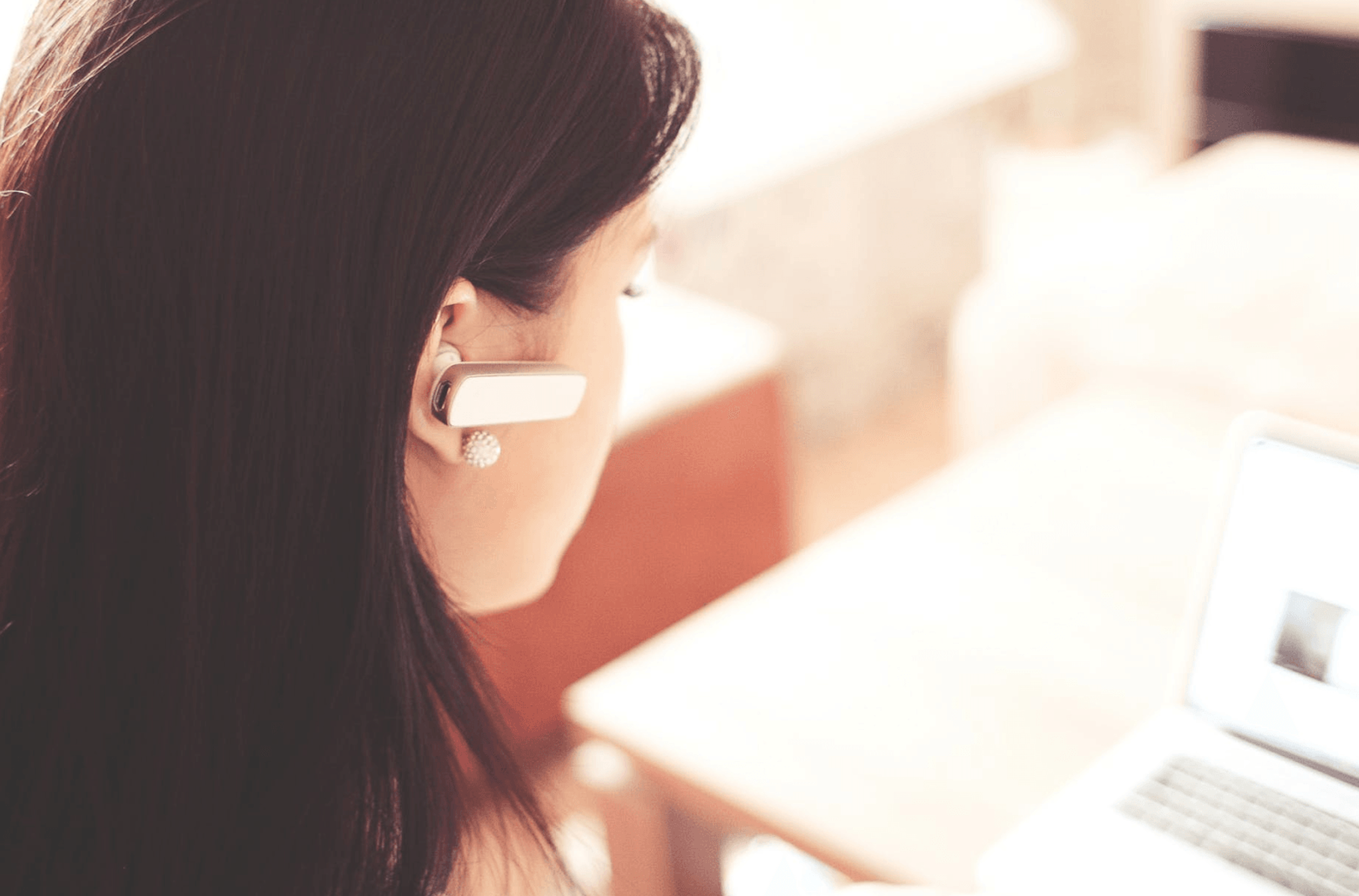 woman working remotely on laptop with earpiece