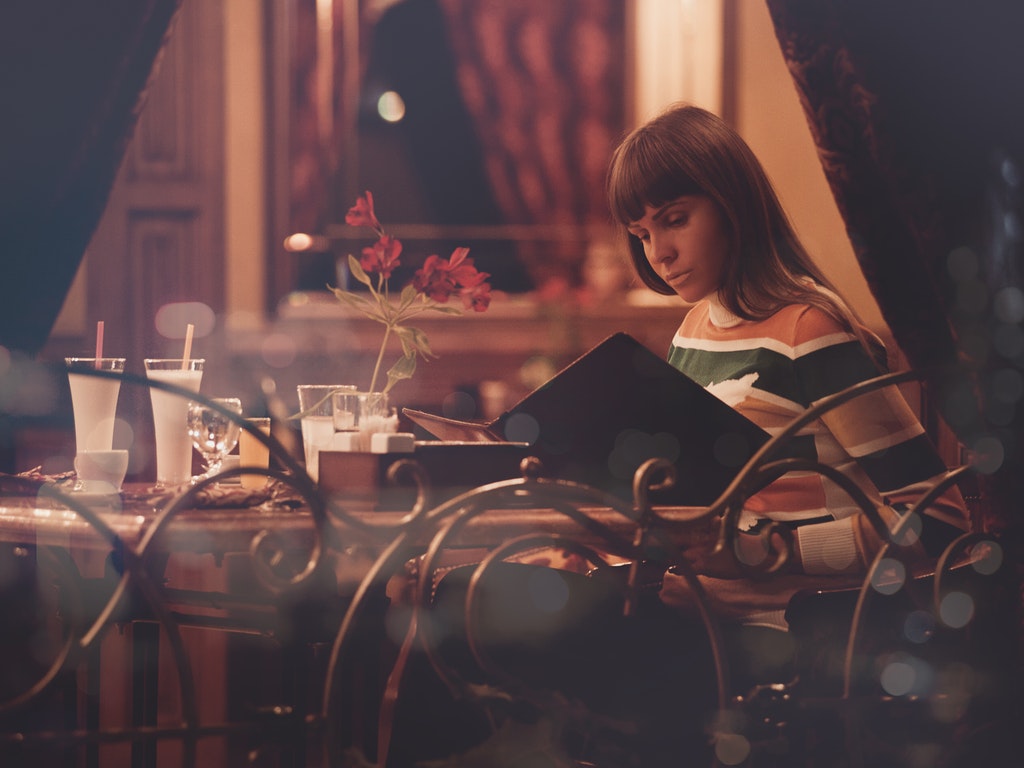 woman reading a menu at a restaurant table