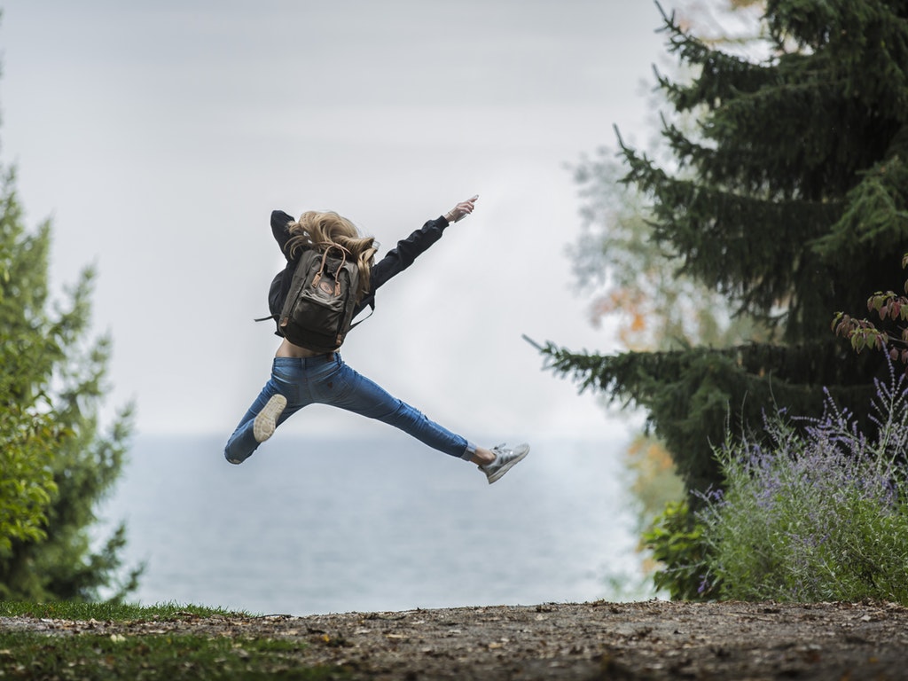 hiker jumping for joy on a trail