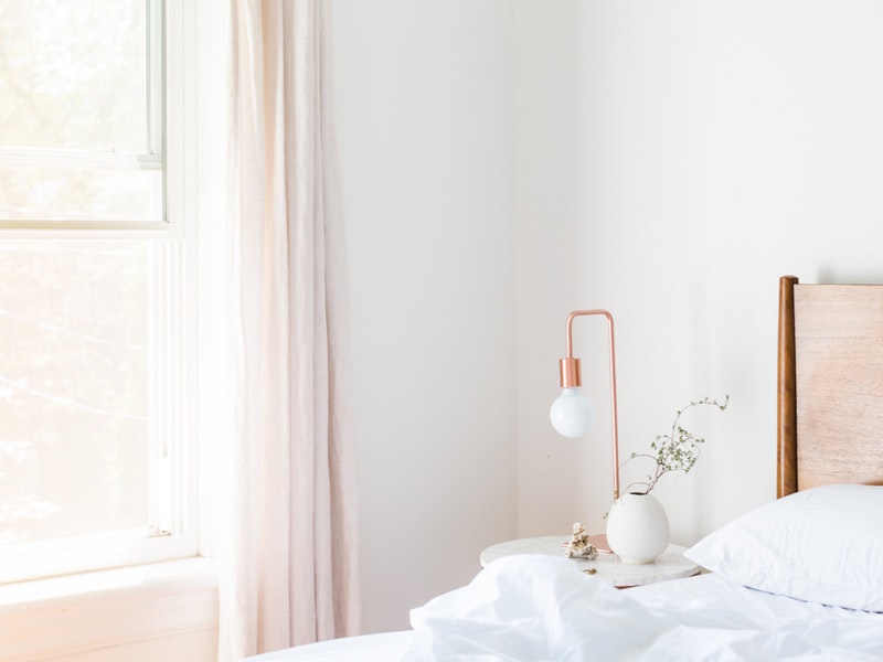 white bedroom with side table and window