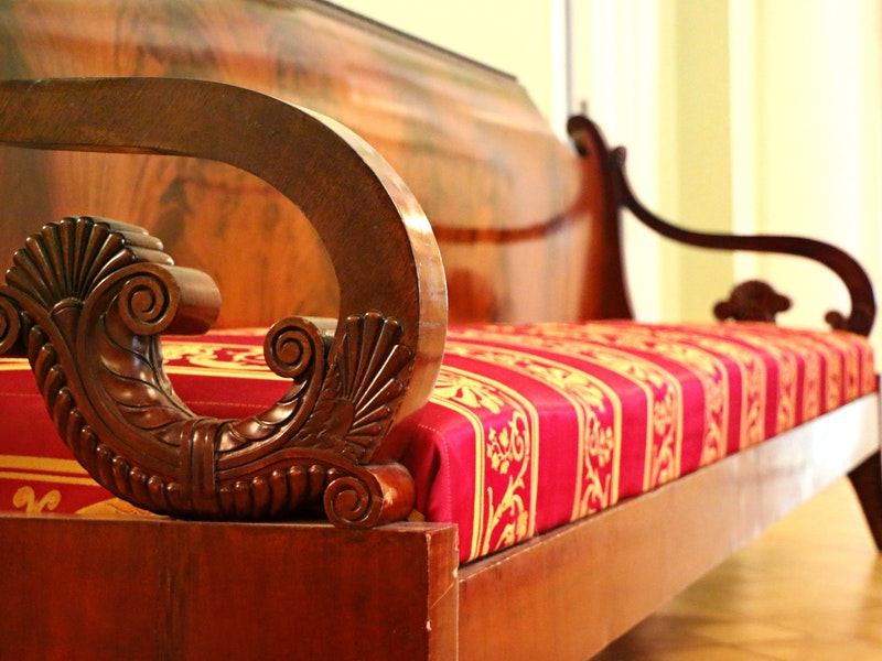 antique couch with red patterned cushion and ornate arm rests