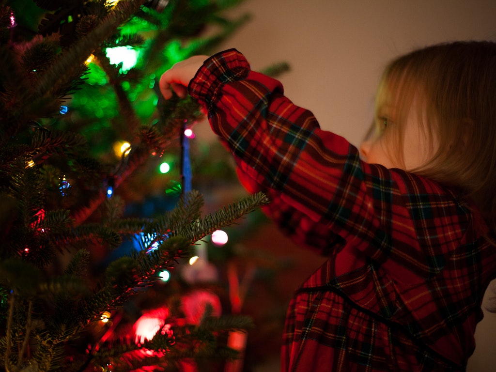 child decorating a christmas tree