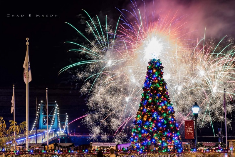 large christmas tree with fireworks and lit bridge in the background