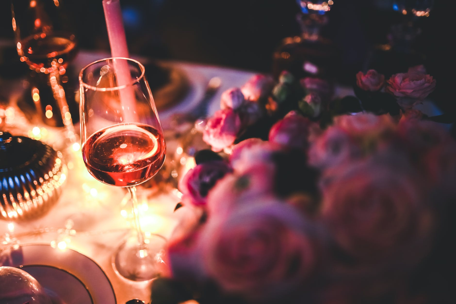 close-up of wine glass next to pink roses