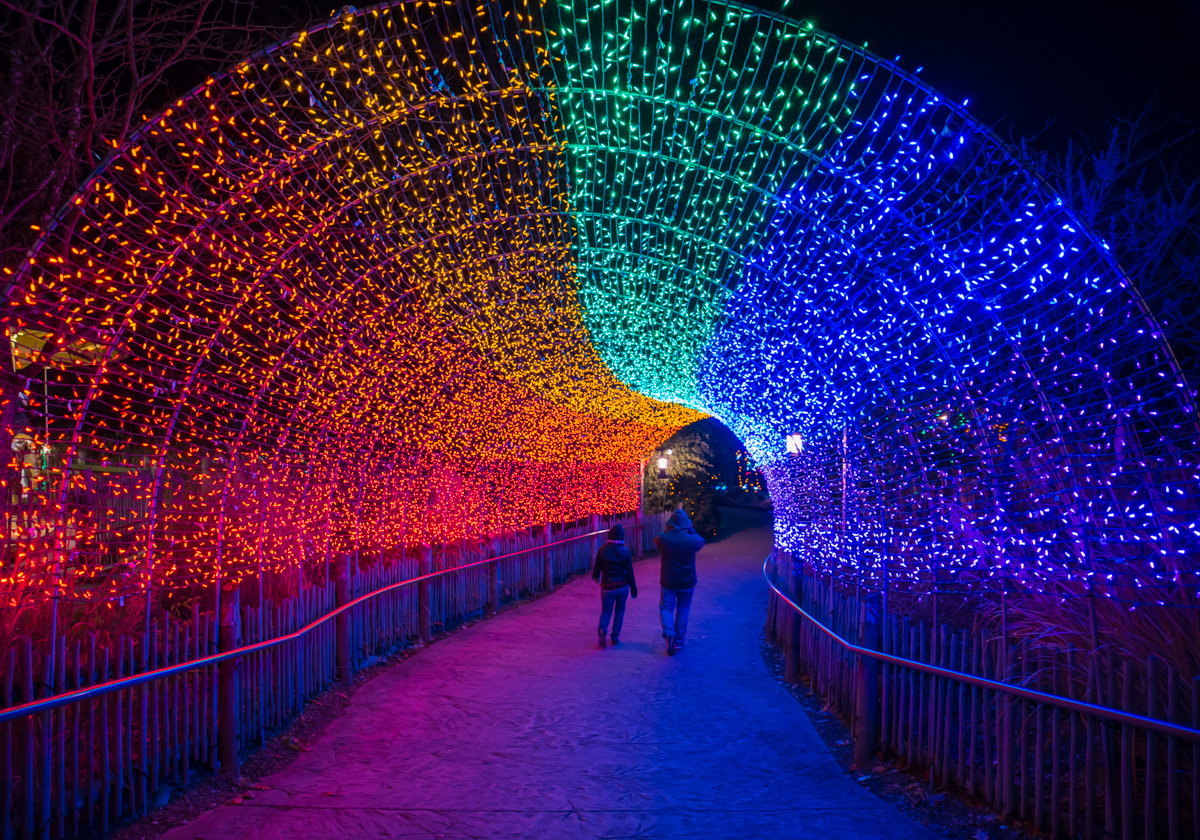 people walking under lit archway at night