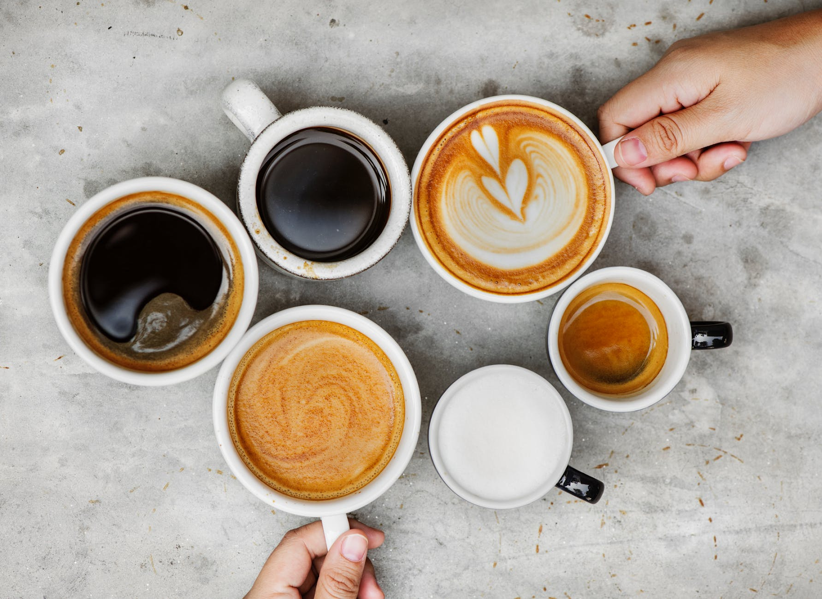 various mugs of coffee, some with latte art