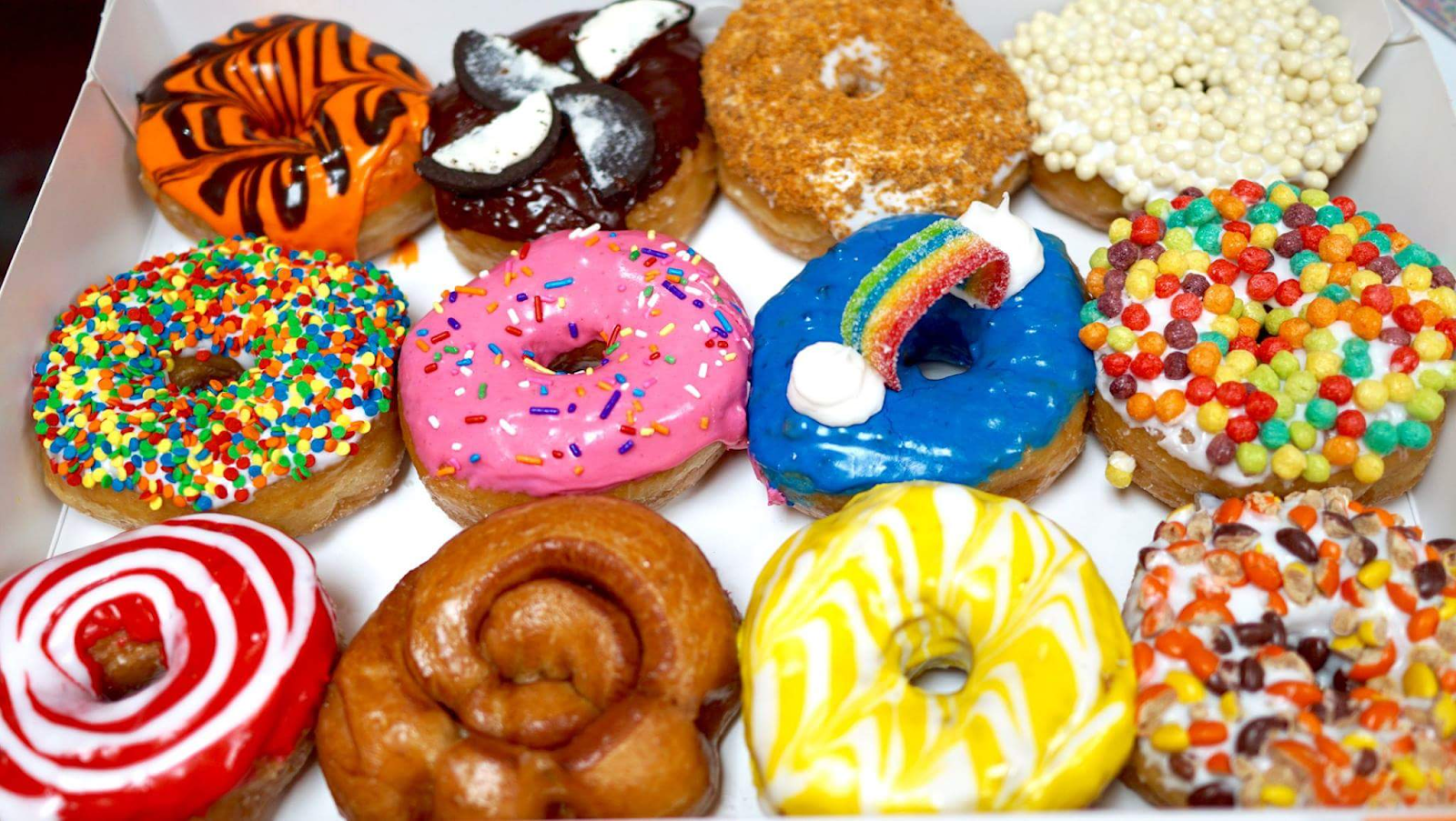 box of a dozen colorfully decorated donuts