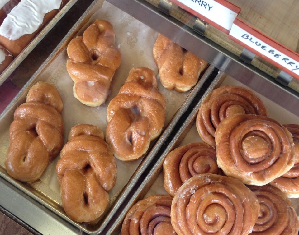 cinnamon rolls & other donuts behind glass at HoneyDip Donuts