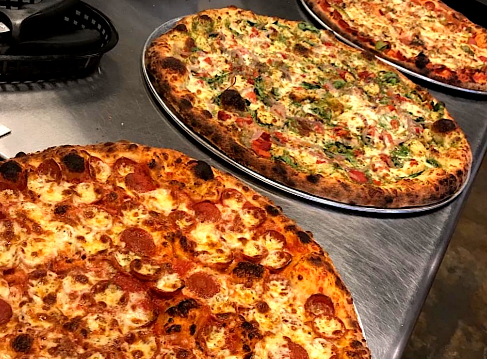 three pizzas under heating light
