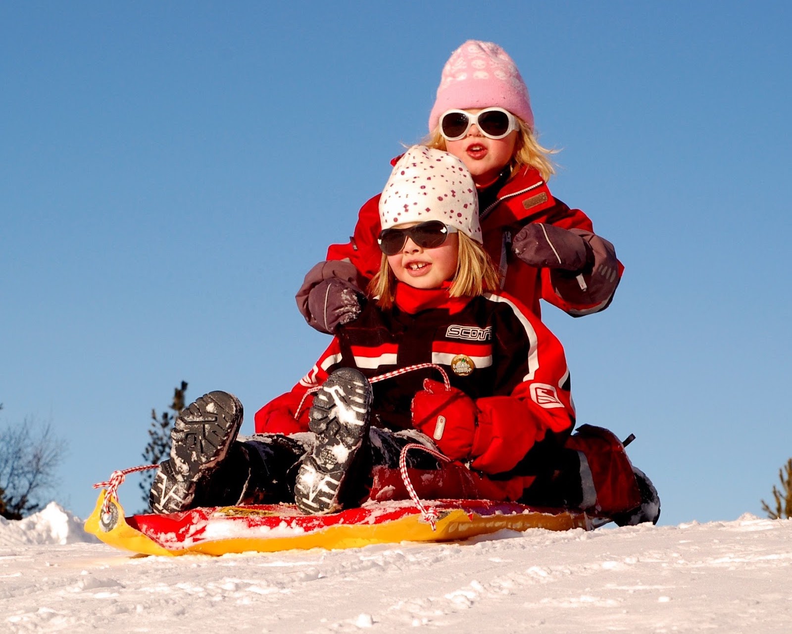little girls sledding down snowy hill