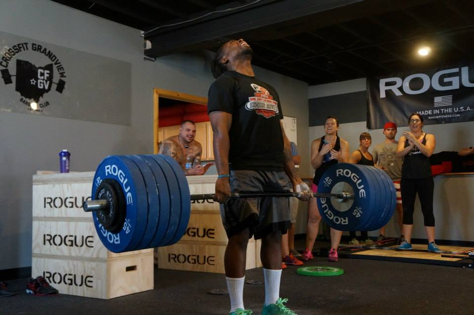 Man powerlifting as group cheers him on