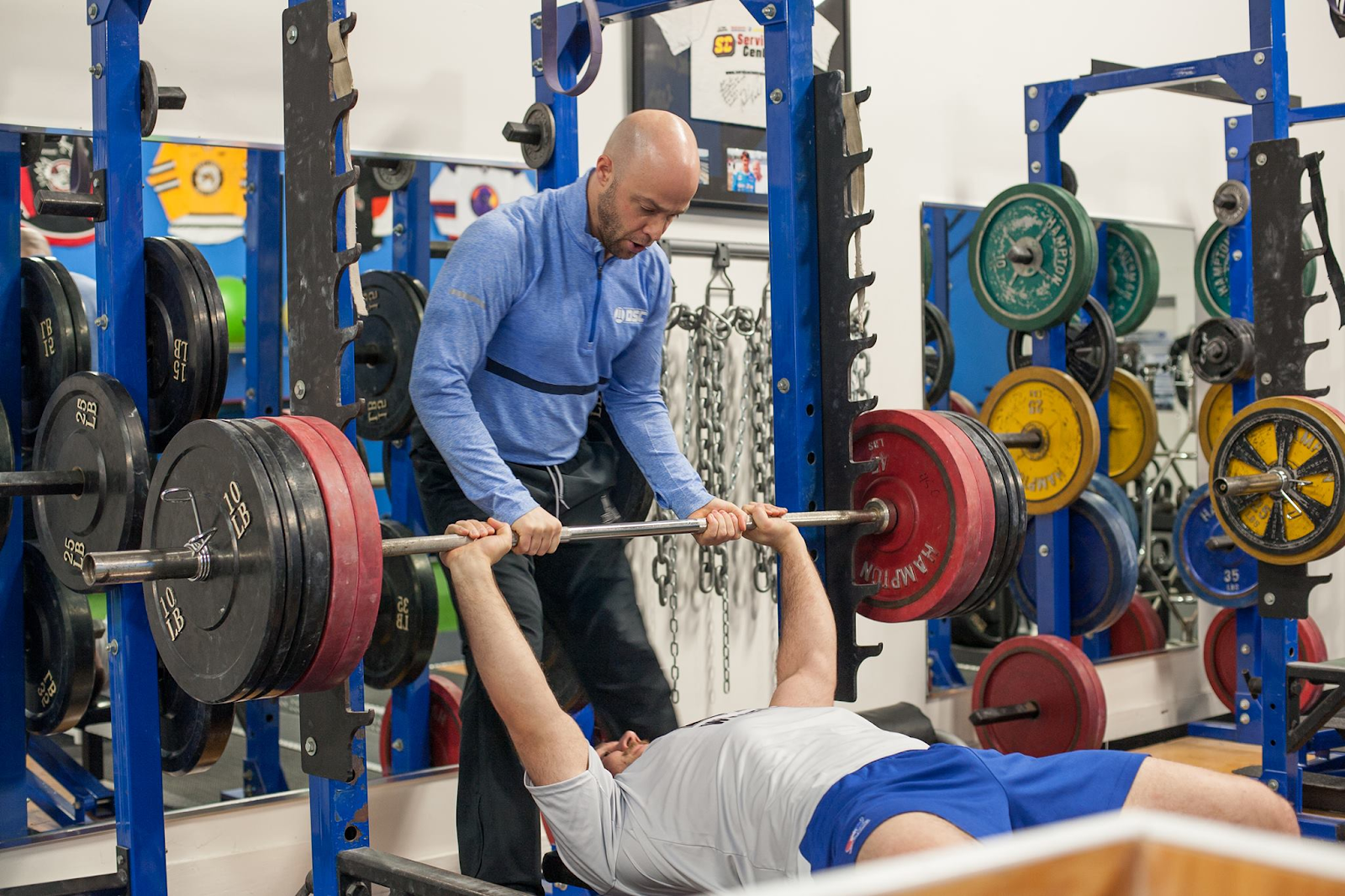 Trainer spotting man bench pressing