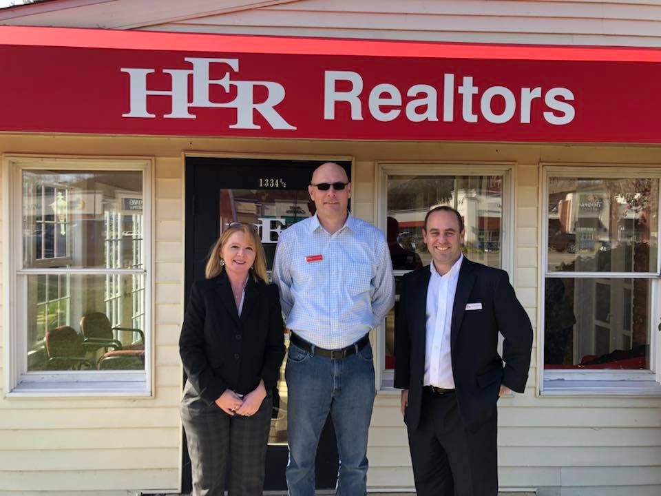 HER, REALTORS® team standing in front of a HER, REALTORS® office