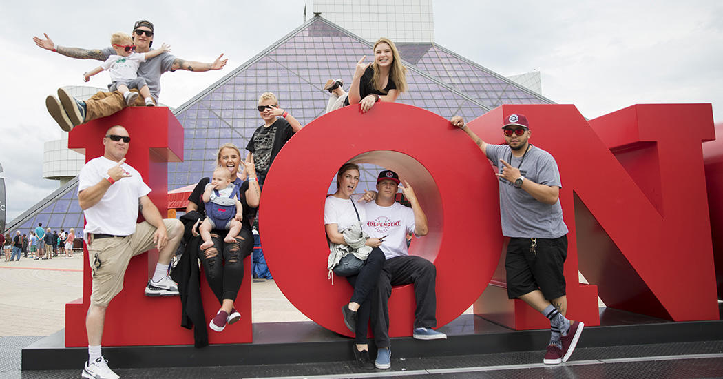 family sitting on large red letters in front of the Rock and Roll Hall of Fame