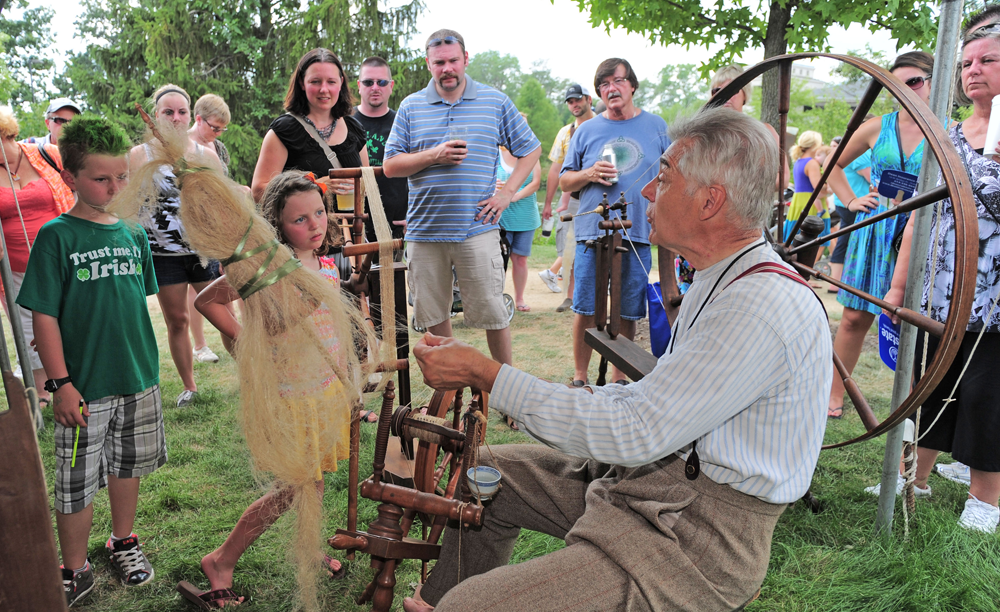 an elderly man demonstrating wool working to children