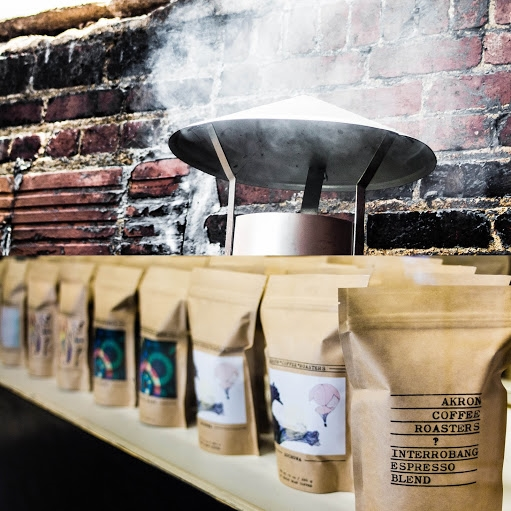 Bags of coffee from Akron Coffee Roasters in front of a rugged brick wall