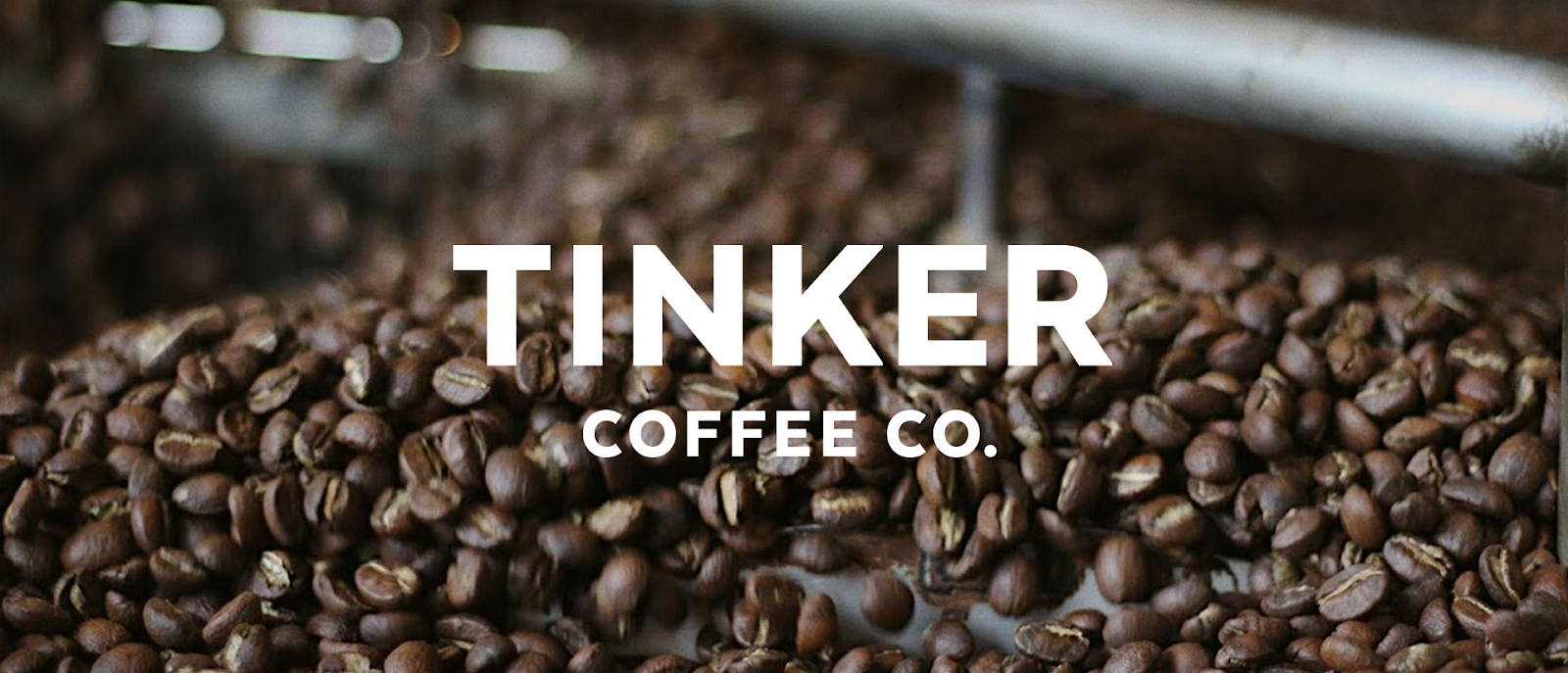 Coffee beans from Tinker, with "Tinker Coffee Co." overlaid on the image in white text